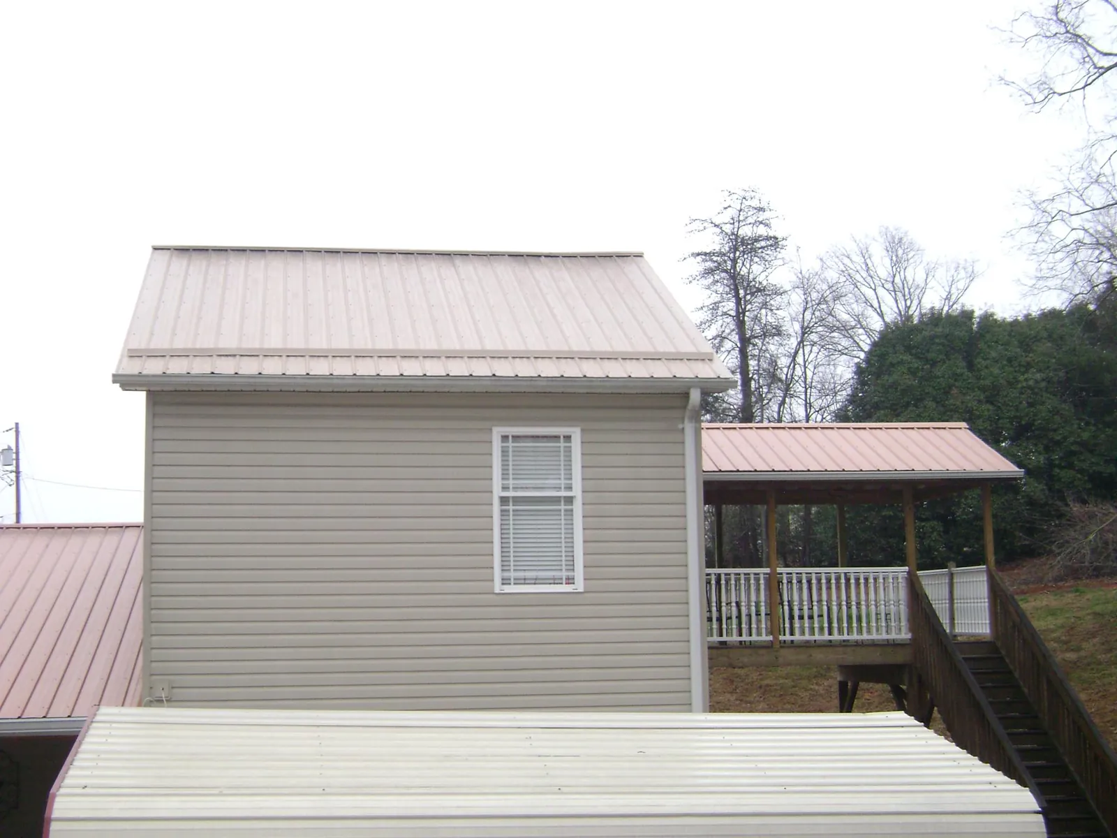Tan metal roofs on a two story addition and attached porch, from a Roof Replacement job in Flat Top